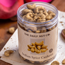 Load image into Gallery viewer, A clear jar filled with Indian spice cashew nuts, with the label 'The Daily Nut Co. Indian Spice Cashews' visible at the top.